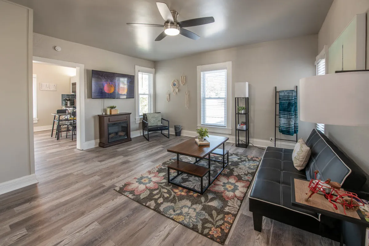 The hero image features a cozy living room with a plush sofa, a stylish coffee table atop a soft rug, and a smart TV set against a backdrop of large windows that let in natural morning light. The space invites guests to unwind, socialize, or enjoy quiet moments with a good book or a movie.