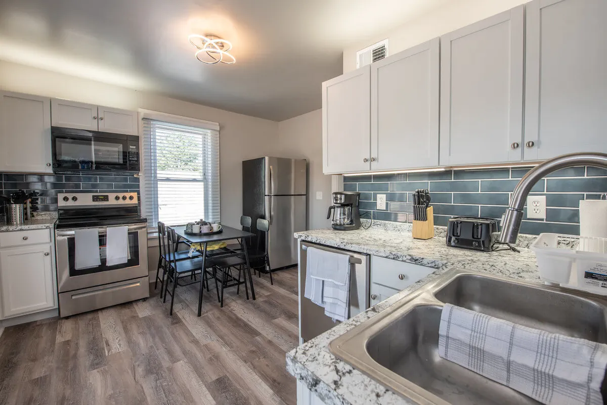 A view of a modern kitchen featuring sleek appliances, polished granite countertops, and a welcoming dining area. The space is set up for cooking and socializing, with ample workspace and contemporary finishes that invite culinary creativity. The kitchen flows seamlessly into the adjoining living area, fostering a sense of openness and connection.